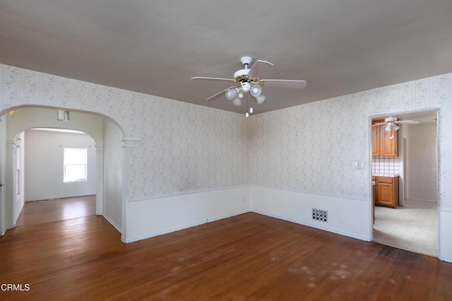 2577 Boulder Rd, Altadena, CA 91001 - unfurnished room featuring ceiling fan, wallpapered walls, wood finished floors, arched walkways, and wainscoting