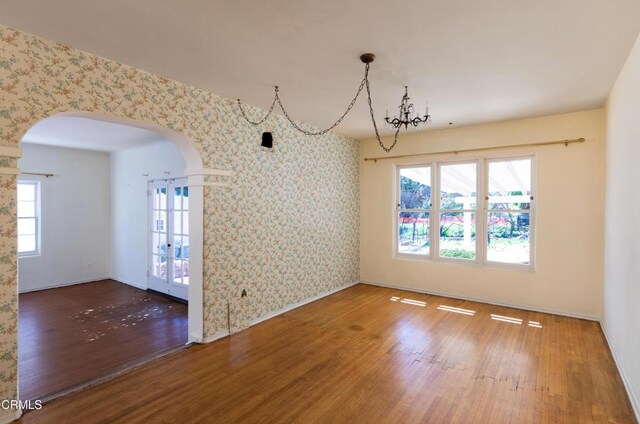 2577 Boulder Rd, Altadena, CA 91001 - unfurnished dining area featuring arched walkways, wood finished floors, wallpapered walls, and french doors