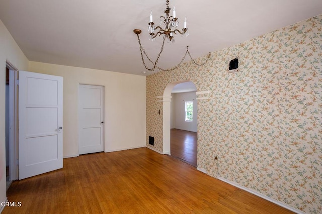 2577 Boulder Rd, Altadena, CA 91001 - empty room featuring wallpapered walls, arched walkways, wood finished floors, and a chandelier