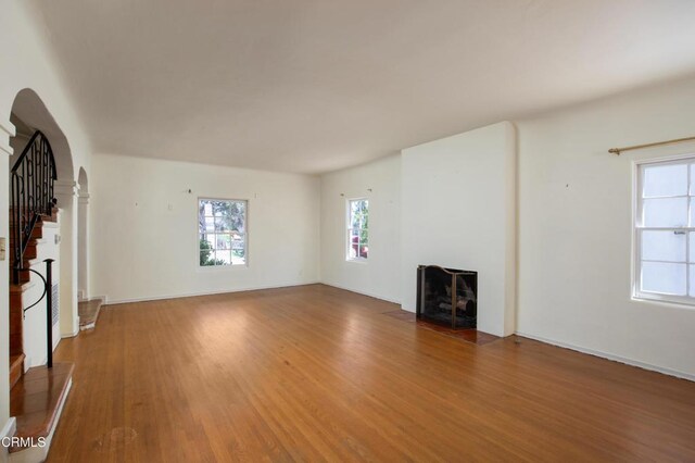 2577 Boulder Rd, Altadena, CA 91001 - unfurnished living room with arched walkways, a fireplace, wood finished floors, and stairway