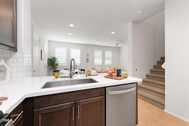 kitchen featuring stainless steel dishwasher, a sink, a peninsula, dark brown cabinetry, and light countertops