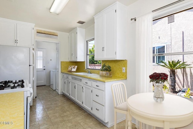 2327 Roscommon Ave, Monterey Park, CA 91754 - kitchen with a sink, white range with gas stovetop, light countertops, washer / clothes dryer, and white cabinets