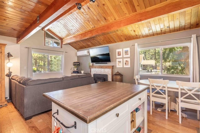945 Tinker Bell Ave, Big Bear City, CA 92314 - kitchen with light wood-type flooring, white cabinets, a wall mounted AC, wooden ceiling, and a tile fireplace