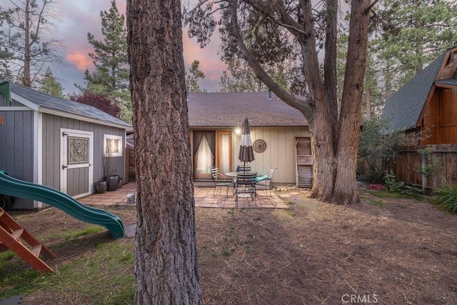 945 Tinker Bell Ave, Big Bear City, CA 92314 - back of property at dusk featuring a patio area, a playground, and a shingled roof