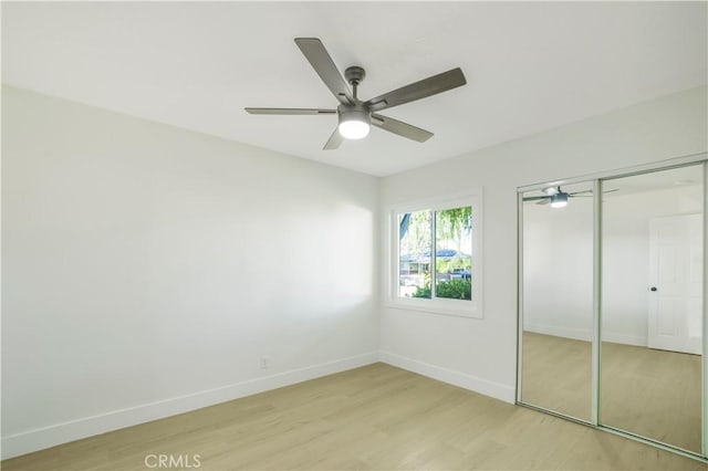 unfurnished bedroom featuring light wood-style flooring, baseboards, a closet, and ceiling fan