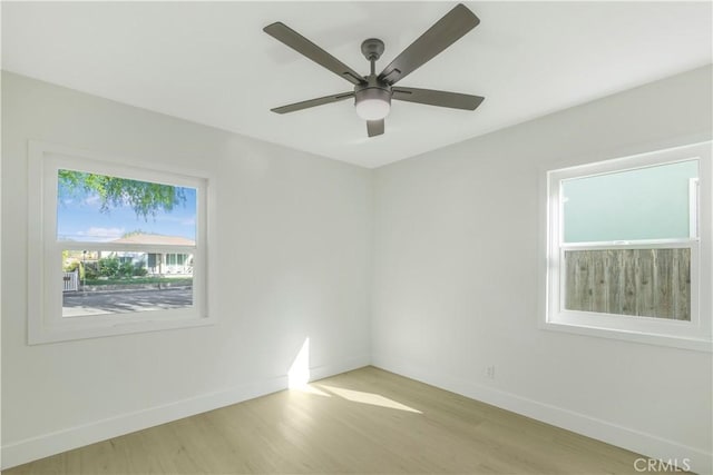 empty room featuring baseboards, light wood-style flooring, and ceiling fan
