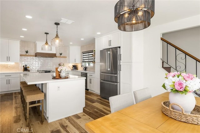 13381 Del Cerro Dr, Tustin, CA 92780 - kitchen featuring appliances with stainless steel finishes, light countertops, white cabinets, wood finished floors, and recessed lighting