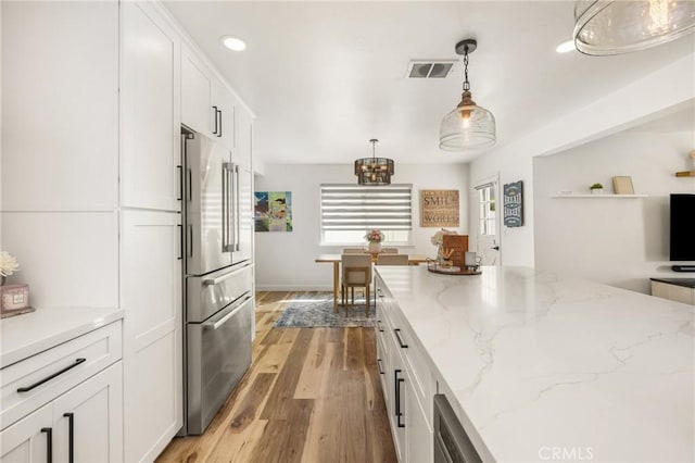 13381 Del Cerro Dr, Tustin, CA 92780 - kitchen with high quality fridge, white cabinets, a chandelier, light wood-style flooring, and pendant lighting