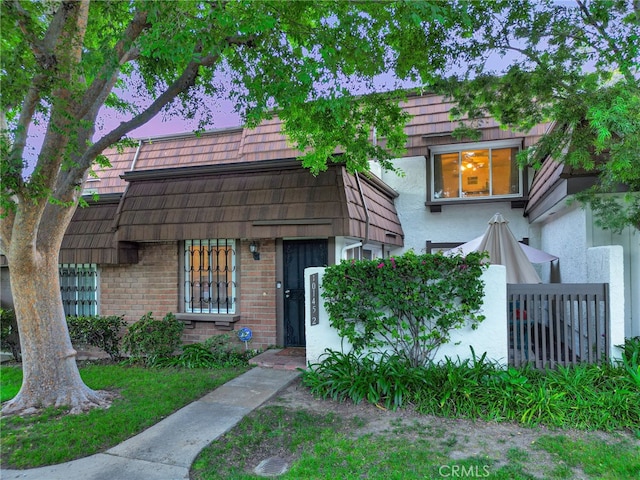 10145 Larwin Ave Unit 2, Chatsworth, CA 91311 - view of front of home with brick siding, mansard roof, stucco siding, and fence