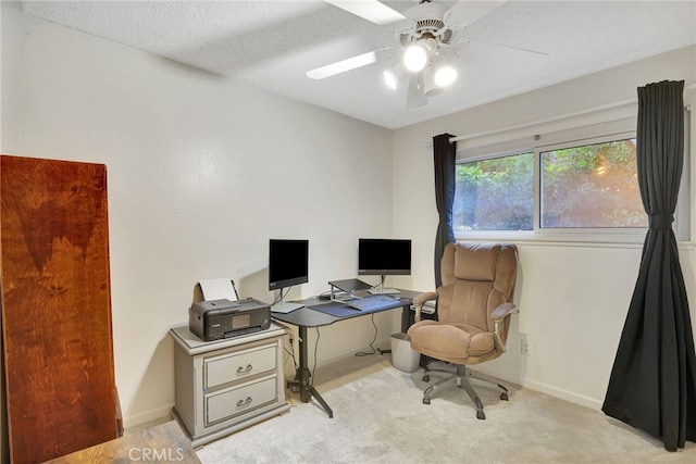office space with light carpet, a ceiling fan, baseboards, and a textured ceiling