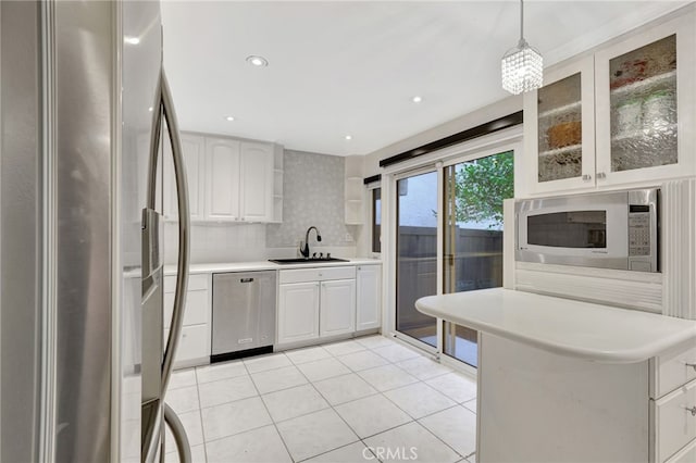 kitchen with stainless steel appliances, a sink, light countertops, light tile patterned floors, and white cabinetry