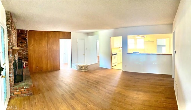 unfurnished living room with wood finished floors, a fireplace, and a textured ceiling
