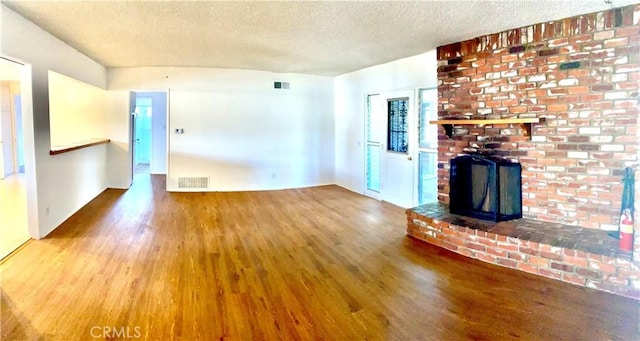 unfurnished living room featuring wood finished floors, a textured ceiling, and a fireplace