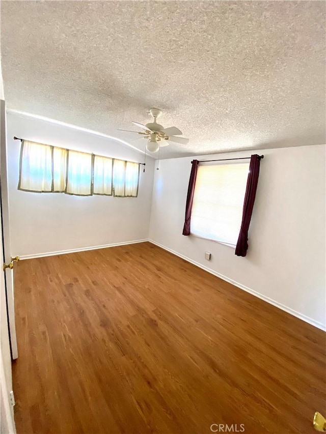 unfurnished room with a textured ceiling, ceiling fan, wood finished floors, and baseboards