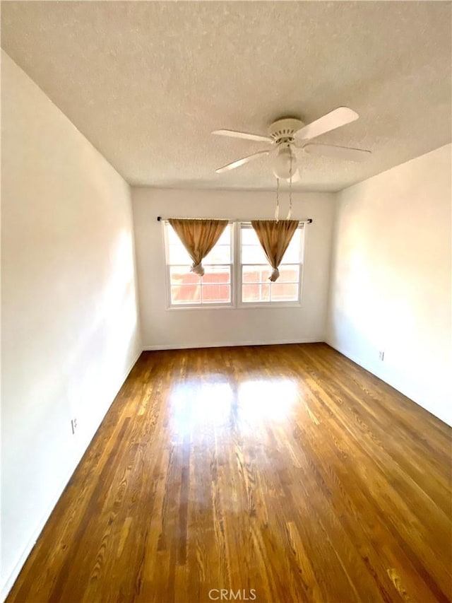 empty room featuring wood finished floors, a textured ceiling, and ceiling fan