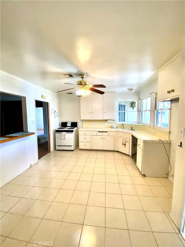kitchen with gas range gas stove, light countertops, ceiling fan, white cabinetry, and light tile patterned floors