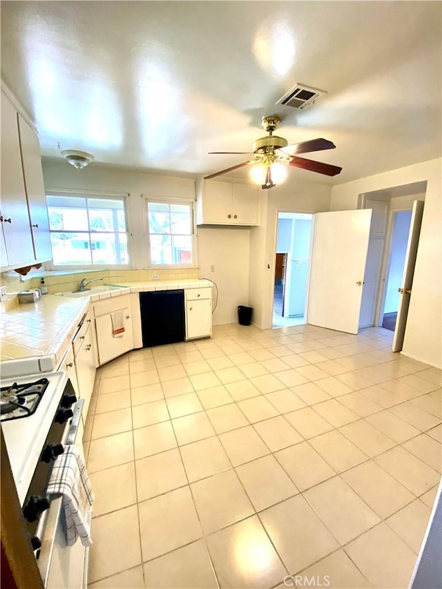 kitchen featuring tile counters, white gas range oven, black dishwasher, white cabinets, and ceiling fan