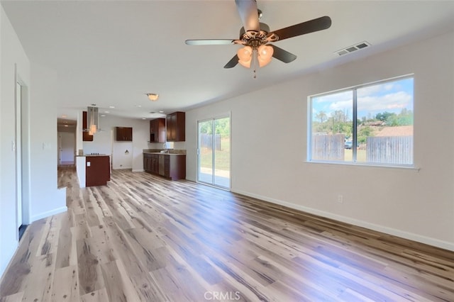 43038 Glacier Ln, Coarsegold, CA 93614 - unfurnished living room featuring a ceiling fan, light wood-type flooring, baseboards, and a sink