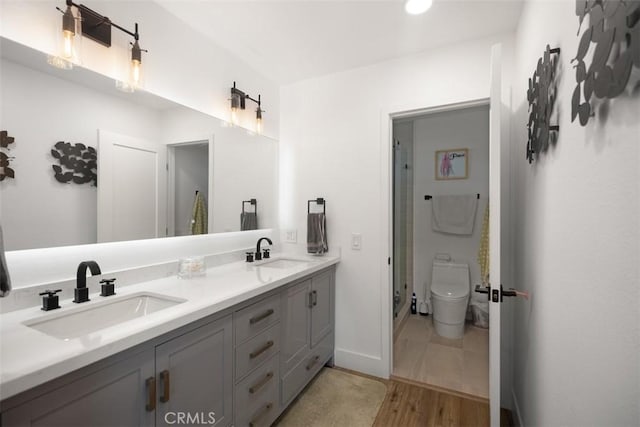 25232 Grissom Rd, Laguna Hills, CA 92653 - bathroom featuring a shower stall, wood finished floors, toilet, double vanity, and baseboards