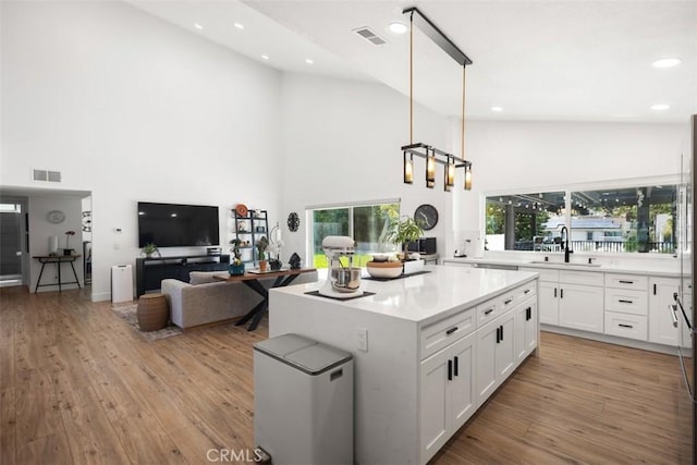25232 Grissom Rd, Laguna Hills, CA 92653 - kitchen with high vaulted ceiling, a sink, light countertops, white cabinetry, and a center island