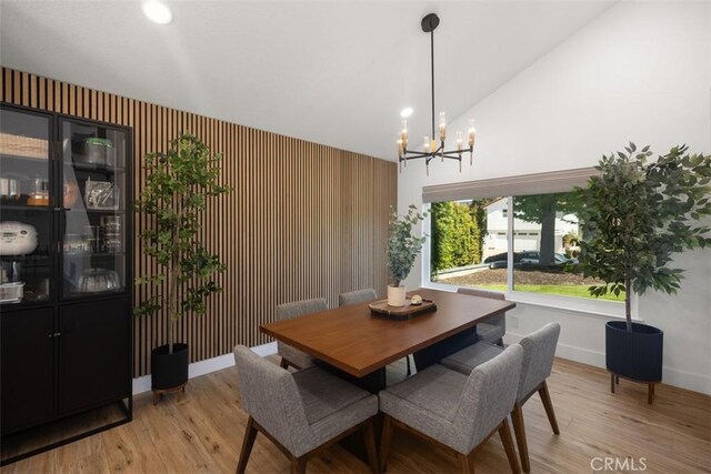 25232 Grissom Rd, Laguna Hills, CA 92653 - dining space featuring a chandelier, baseboards, light wood finished floors, high vaulted ceiling, and an accent wall