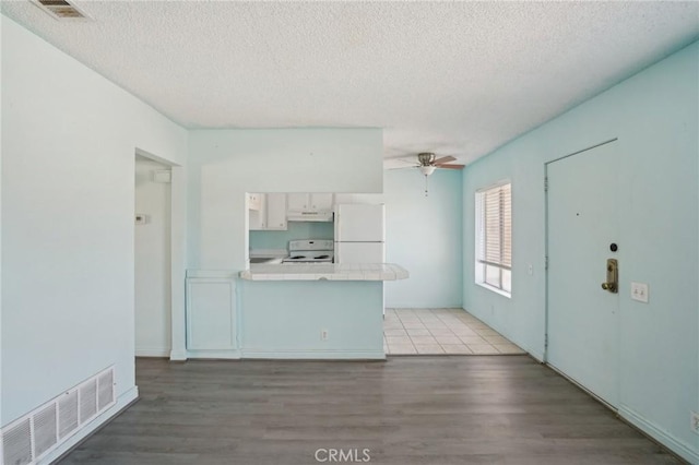 82075 Country Club Dr Unit 31, Indio, CA 92201 - kitchen featuring white appliances, tile counters, under cabinet range hood, light wood-style flooring, and a textured ceiling