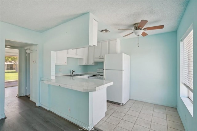 82075 Country Club Dr Unit 31, Indio, CA 92201 - kitchen featuring white appliances, tile counters, a sink, ceiling fan, and a peninsula