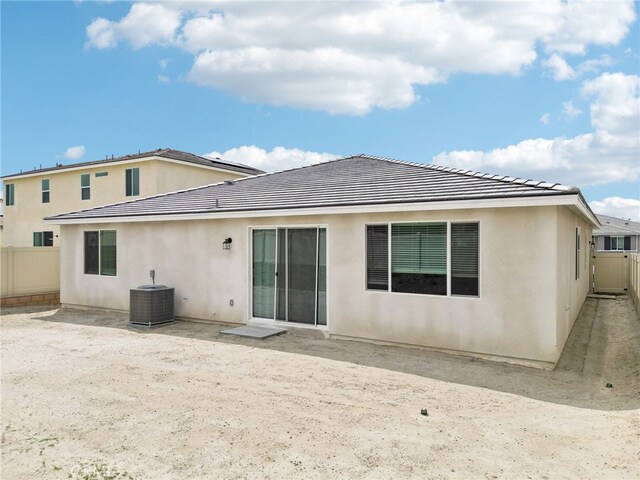 rear view of house with central AC unit, a fenced backyard, stucco siding, and a tiled roof
