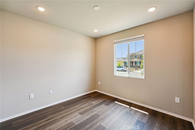 spare room with dark wood-style floors, baseboards, and recessed lighting