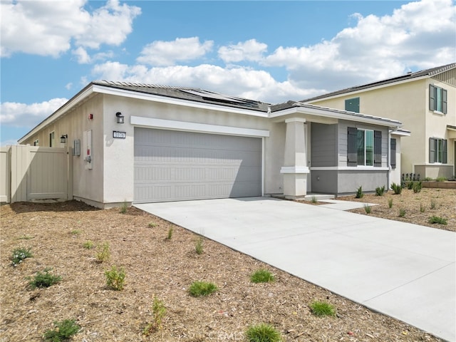view of front of property with a garage, roof mounted solar panels, driveway, fence, and stucco siding