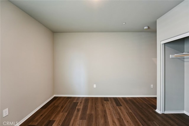 unfurnished bedroom with dark wood-style floors, baseboards, and a closet
