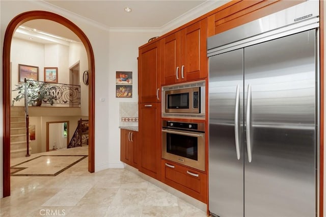 24182 Torena Cir, Mission Viejo, CA 92691 - kitchen with built in appliances, arched walkways, baseboards, ornamental molding, and brown cabinets