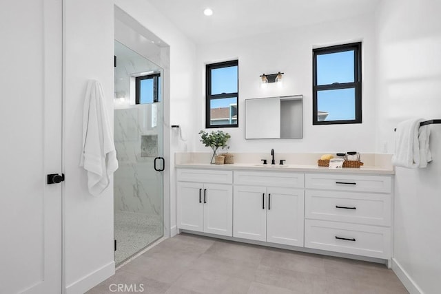 bathroom with a marble finish shower, vanity, and baseboards