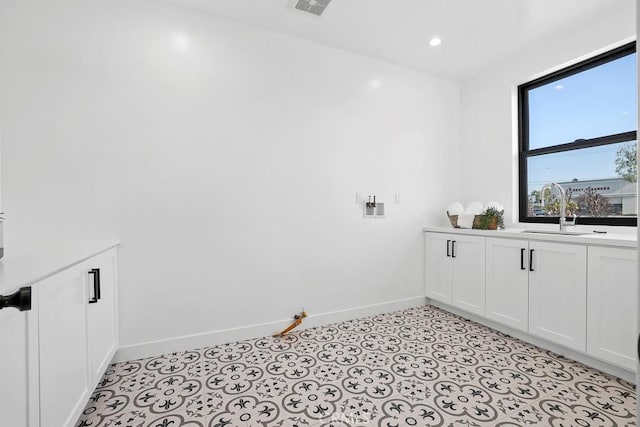 laundry room featuring a sink, baseboards, and light flooring
