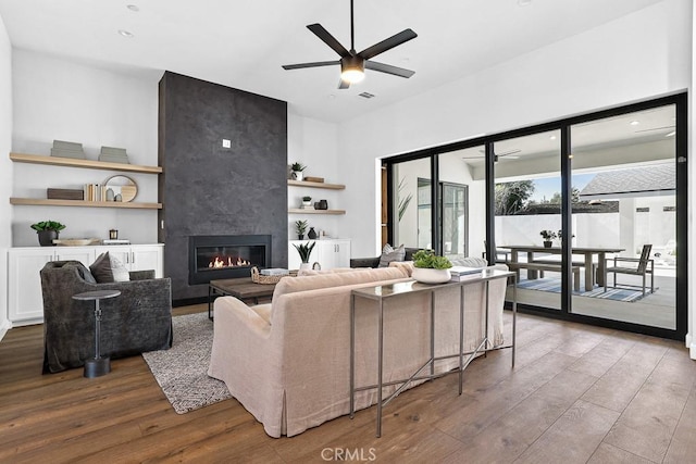 living area with hardwood / wood-style flooring, ceiling fan, a large fireplace, recessed lighting, and built in shelves