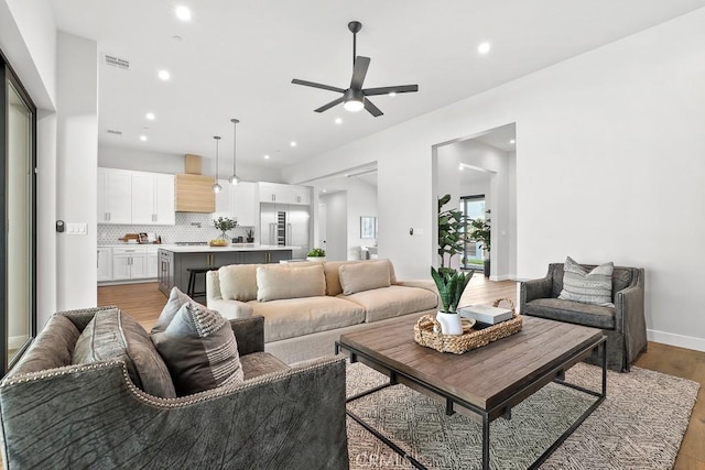 living room featuring ceiling fan, recessed lighting, light wood finished floors, and baseboards