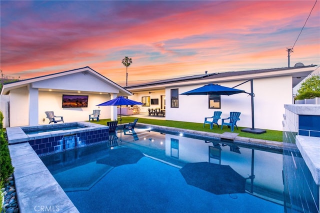 back of property at dusk with stucco siding, a patio area, and outdoor dining area