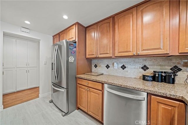 19439 Oak Crossing Rd, Newhall, CA 91321 - kitchen featuring stainless steel appliances, backsplash, brown cabinetry, recessed lighting, and light stone countertops