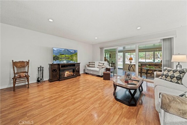 19439 Oak Crossing Rd, Newhall, CA 91321 - living area featuring light wood-type flooring, a glass covered fireplace, and recessed lighting