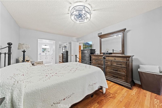 19439 Oak Crossing Rd, Newhall, CA 91321 - bedroom featuring light wood-type flooring, a textured ceiling, and connected bathroom