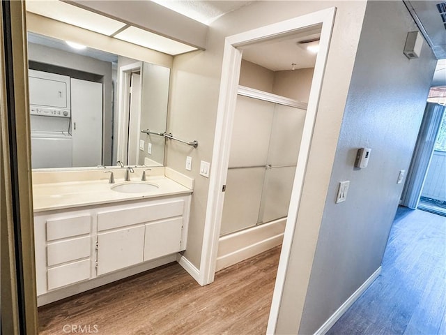 2474 Pleasant Way Unit E, Thousand Oaks, CA 91362 - bathroom featuring estacked washer and dryer, wood finished floors, vanity, and shower / bath combination with glass door