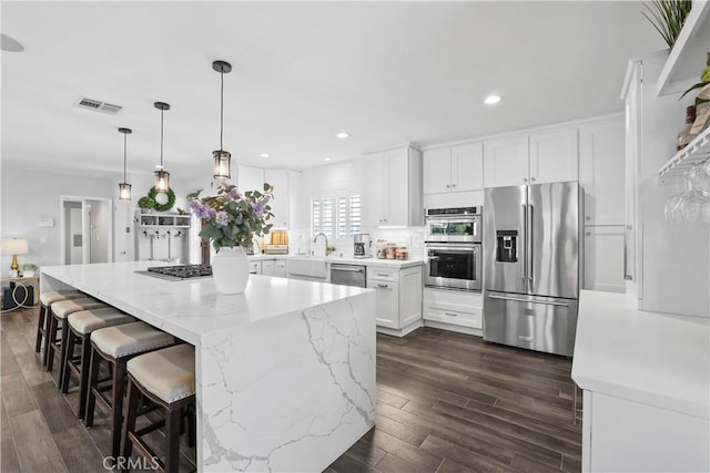 835 S Terri Ann Dr, West Covina, CA 91791 - kitchen with appliances with stainless steel finishes, dark wood finished floors, white cabinets, recessed lighting, and a kitchen island