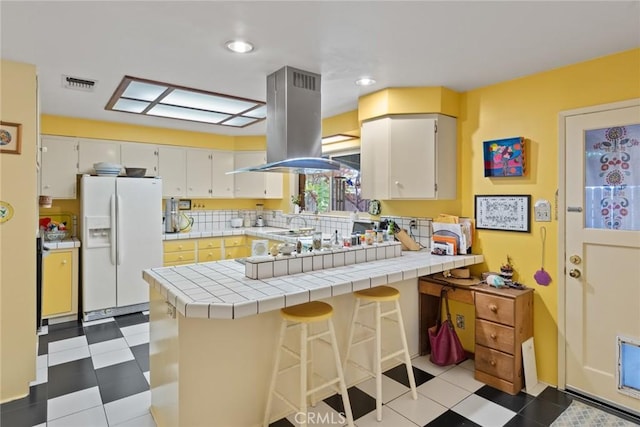 297 Connors Ave, Chico, CA 95926 - kitchen with white refrigerator with ice dispenser, island range hood, a peninsula, dark floors, and white cabinets