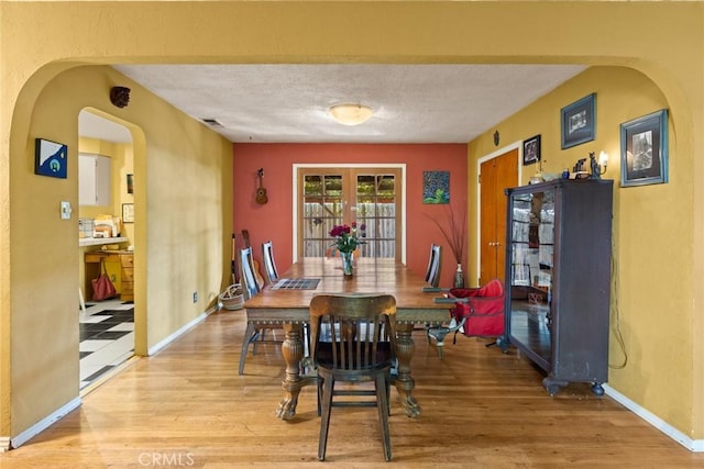 297 Connors Ave, Chico, CA 95926 - dining room featuring wood finished floors, arched walkways, a textured ceiling, baseboards, and french doors