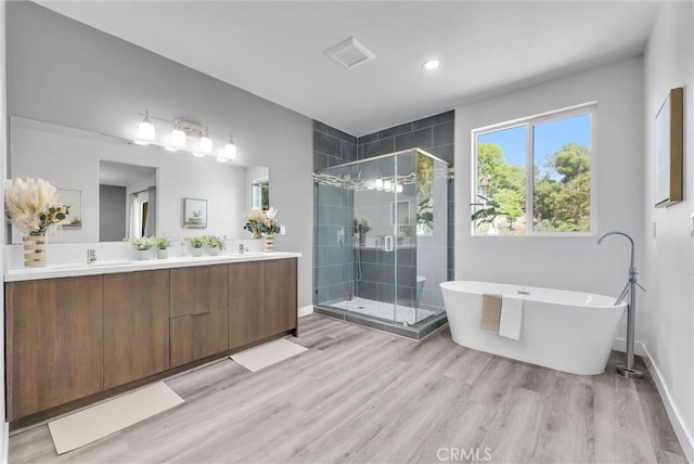689 Castlehill Dr, Walnut, CA 91789 - bathroom featuring wood finished floors, a stall shower, a soaking tub, double vanity, and recessed lighting