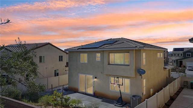 36927 Arezzo Ct, Beaumont, CA 92223 - back of property at dusk with stucco siding, a fenced backyard, central air condition unit, and roof mounted solar panels