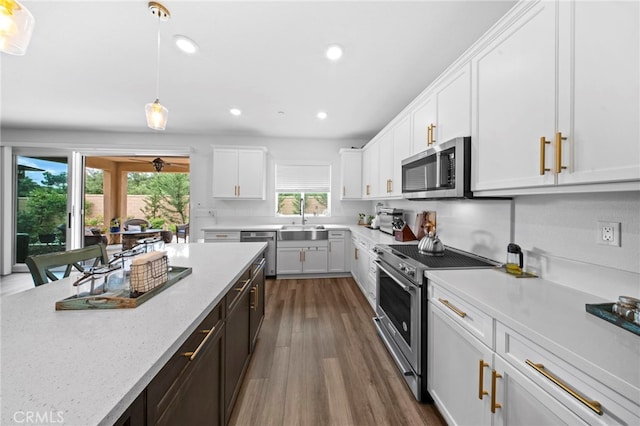 2569 Pasture Gln, Escondido, CA 92029 - kitchen with appliances with stainless steel finishes, a sink, dark wood finished floors, white cabinets, and hanging light fixtures