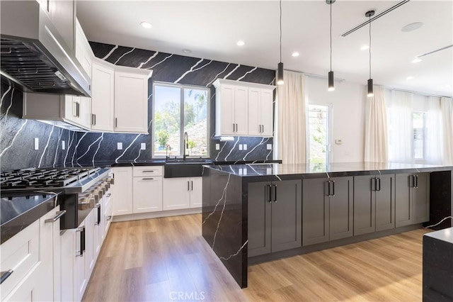 17195 Summit Hills Dr, Canyon Country, CA 91387 - kitchen with extractor fan, a sink, stainless steel gas cooktop, light wood-style floors, and a large island