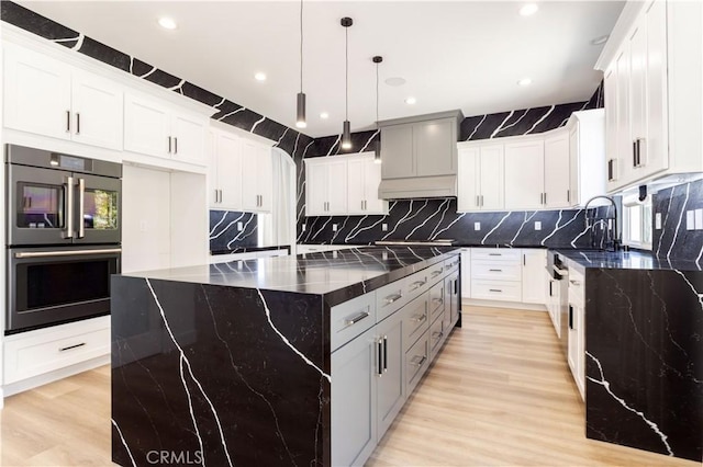 17195 Summit Hills Dr, Canyon Country, CA 91387 - kitchen with multiple ovens, a kitchen island, dark stone counters, light wood finished floors, and tasteful backsplash