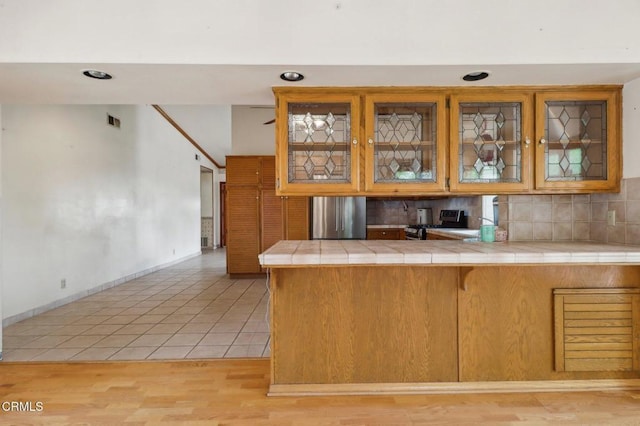22573 Honnold Dr, Santa Clarita, CA 91350 - kitchen featuring tile counters, stainless steel fridge, decorative backsplash, baseboards, and a peninsula